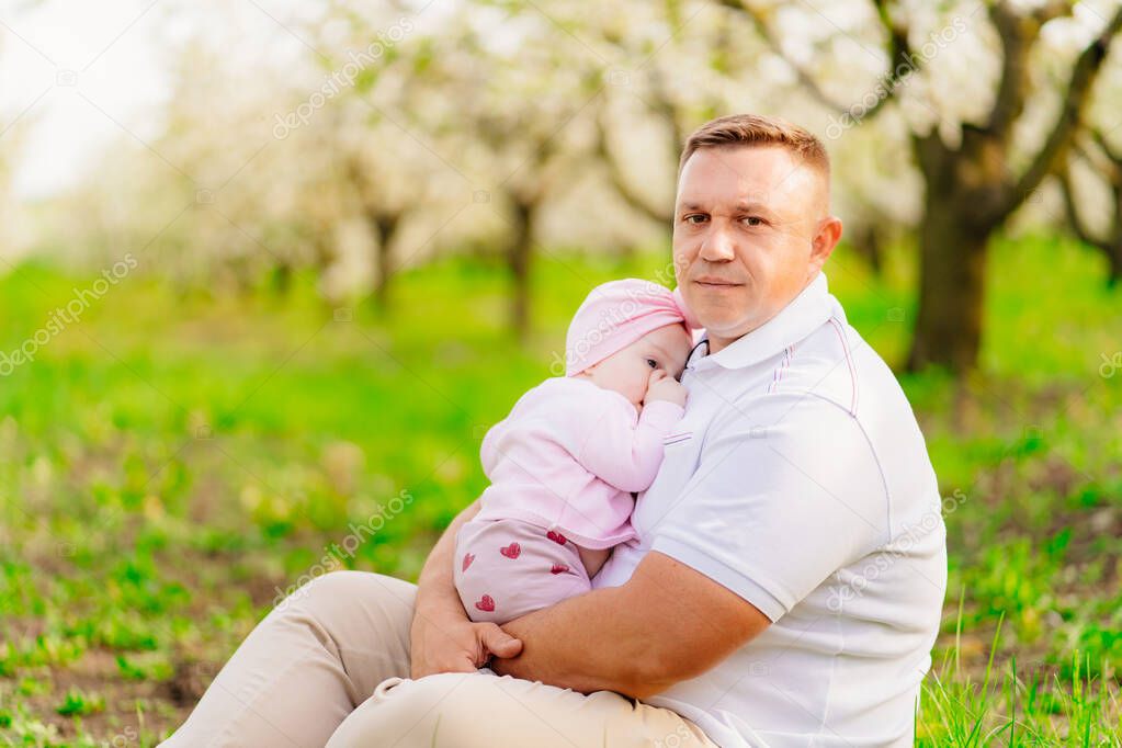 dad with a baby daughter. the baby wants to sleep and sucks her finger