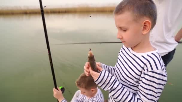 Un garçon tient un poisson capturé lors d'un voyage de pêche — Video