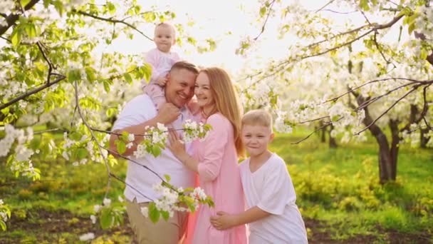 Famille avec fils et fille au jardin fleuri de printemps. fente labiale chez les nourrissons. — Video
