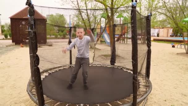 Хлопець стрибає на батуті. розваги для дітей на відкритому повітрі . — стокове відео