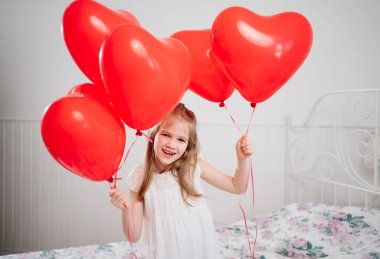 Kırmızı balonlu komik kız beyaz duvarda gülümseyen kalpler şeklinde.