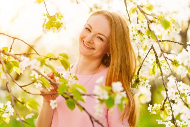 Bahar parkında çiçek açan ağacın yanında çekici bir kadın. Kiraz Bahçesi. Güneş parıltısı