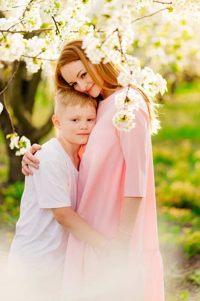 Мать и сын подросток в цветущем весеннем вишневом саду. — стоковое фото