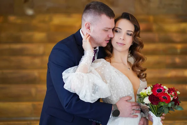 Una bella coppia di sposi con un bouquet. sposa accarezza delicatamente lo sposo sul viso — Foto Stock