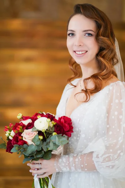 Retrato de uma noiva com cachos longos, em um vestido elegante com um buquê — Fotografia de Stock