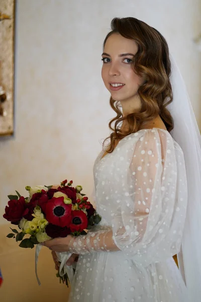 美丽的新娘，留着长长的卷发，穿着华丽的婚纱，戴着花束 — 图库照片