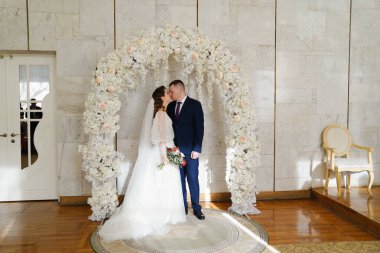 Güzel ve mutlu gelin ve damat düğün töreninde bir çiçek kavisinde