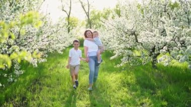 Oğulları olan bir anne çiçek bahçesinde yürür. Kollarındaki en küçük çocuk