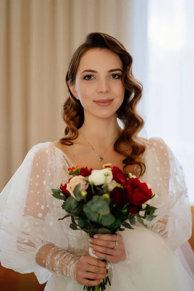 Belle mariée avec de longues boucles, dans une robe élégante avec un bouquet — Photo