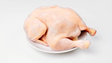 Beyaz arka planda beyaz bir tabakta çiğ tavuk leşi.. 