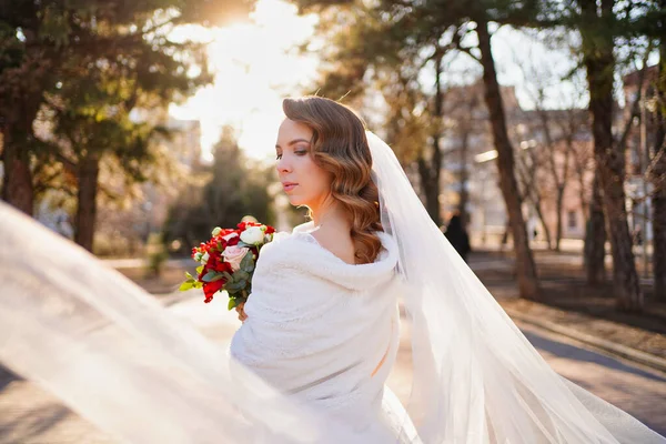 Schöne und glückliche Braut mit weißem Schleier und einem Strauß. — Stockfoto