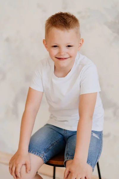 Boy in a white T-shirt and denim shorts. psychological help waiting for kid. — Fotografia de Stock