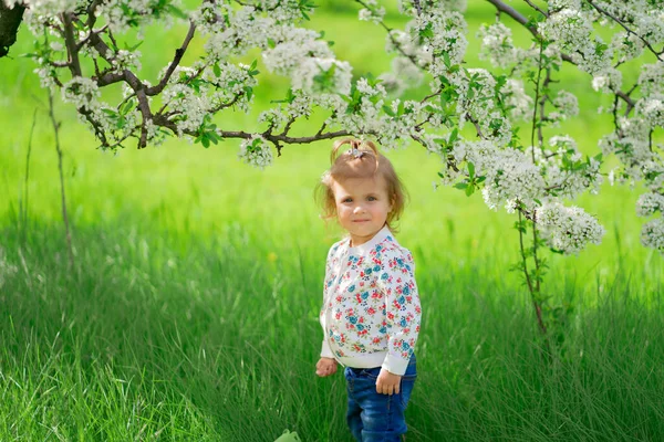 Küçük kız çiçek açan bir bahar bahçesinde duruyor. Çocuklarda mevsimsel alerji — Stok fotoğraf