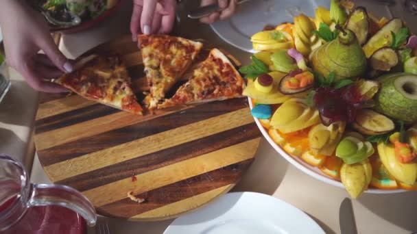 Little hand picks up a piece of pizza from the plate. assorted fresh fruit — Vídeos de Stock