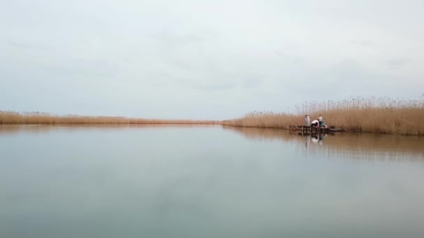 Over de rivier vliegen. familie vissen op een kleine brug bij de rivier. — Stockvideo