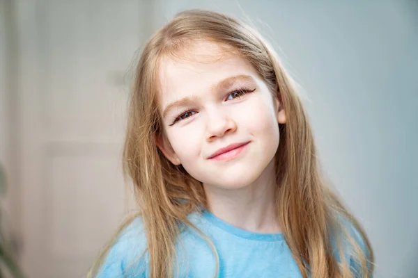 En liten flicka med långt blont hår gjorde en make-up, drog pilar på ögonlocken. — Stockfoto