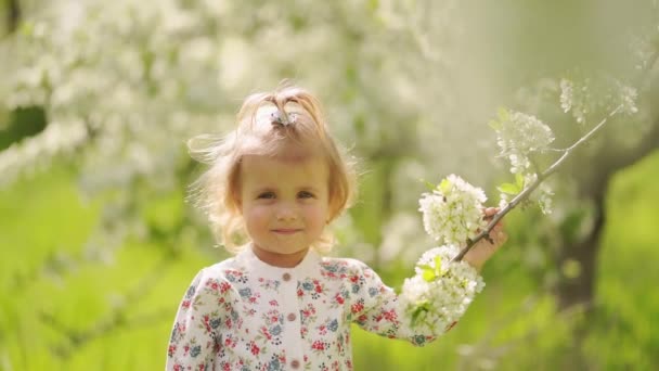 Niña en el árbol floreciente en el jardín. alergias estacionales en niños. — Vídeos de Stock