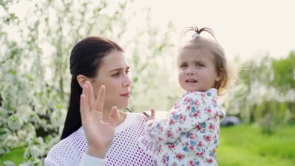 Mutter mit Tochter im Arm verabschiedet sich, verabschiedet sich und winkt mit der Hand — Stockvideo