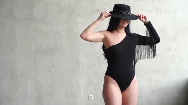 Bella e sexy donna in un body nero e cappello al muro grigio. — Video Stock