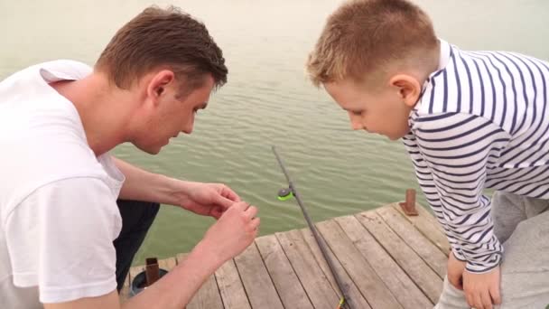 Pai e filho em uma viagem de pesca. um homem amarrado um verme em um gancho de pesca. — Vídeo de Stock