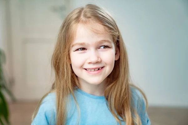 En liten flicka med långt blont hår gjorde en make-up, drog pilar på ögonlocken. — Stockfoto