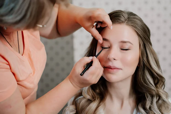 Krásná dívka s dlouhými vlasy dělat oční make-up. — Stock fotografie
