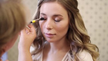 Uzun saçlı güzel bir kız göz makyajı yapıyor.. 