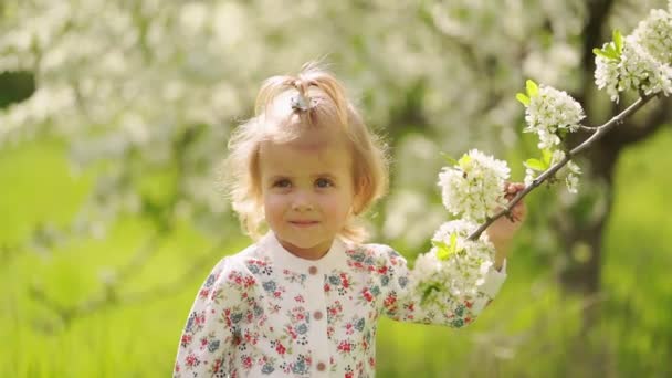 Niña en el árbol floreciente en el jardín. alergias estacionales en niños. — Vídeos de Stock