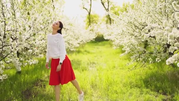 Vacker ung kvinna går genom blommande träd. naturliga kosmetika och parfymer. — Stockvideo