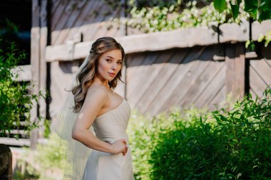 Tahta eski çitin bahçesinde uzun dalgalı saçlı gelin.