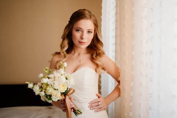 Portrait d'une belle mariée avec un bouquet près de la fenêtre. Traditions de mariage. — Photo