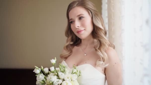 Hermosa novia con un ramo junto a la ventana. Tradiciones de boda. — Vídeo de stock