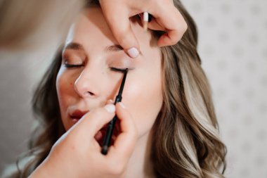 Kapat. Uzun saçlı güzel bir kız göz makyajı yapıyor.. 