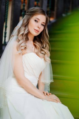 Güzel ve nazik gelin, koyu ahşap bir merdivende oturur. 