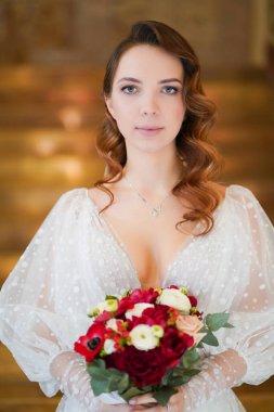 Uzun bukleli bir gelin portresi, zarif bir elbise ve bir buket