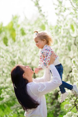 Anne kızını bir çiçek ağacının yanına fırlatıyor. Mutlu çocukluk. 