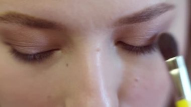 Kapat. Uzun saçlı güzel bir kız göz makyajı yapıyor.. 