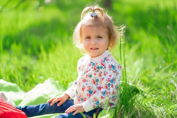 Pequeña linda chica en el césped verde en el parque. —  Fotos de Stock