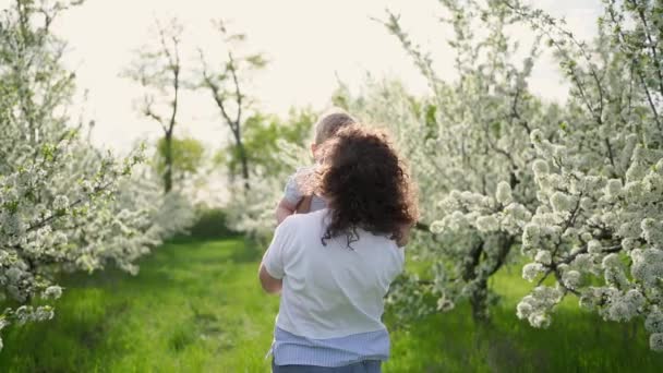 Мама грається на весняному городі з малим сином, викручує і підкидає його.. — стокове відео