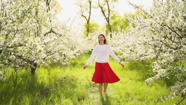 Vacker ung kvinna går genom blommande träd. naturliga kosmetika och parfymer. — Stockvideo