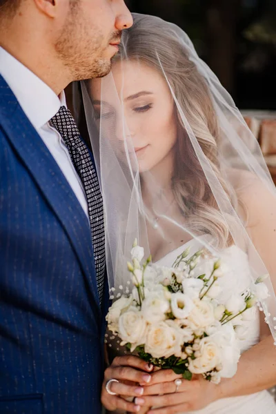 La dulce novia bajo el velo y el novio. hermosos y románticos recién casados. — Foto de Stock