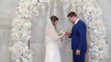 Güzel ve mutlu gelin ve damat çiçek kemerinde yüzüklerini değiş tokuş ederler.