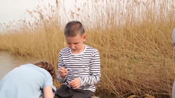 The boy helps the girl to strung worm on a fishing hook — Stock Video