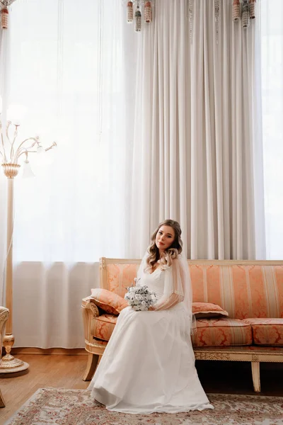 Portrait d'une belle mariée avec un bouquet sur le canapé. Traditions de mariage. — Photo