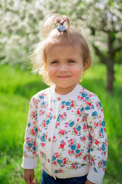 Маленька мила дівчинка на зеленому газоні в парку . — стокове фото