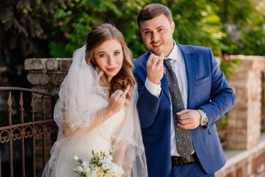 Gelin ve damat, eski çitlerin yanında duran alyansları gösteriyor. 