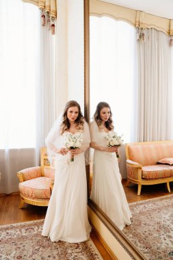 Büyük aynada elinde buketi olan güzel bir gelin. Düğün gelenekleri..