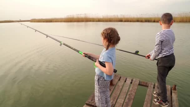 渔民。小女孩和男孩站在一座木桥上，用钓竿钓鱼 — 图库视频影像