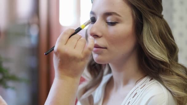 Ein schönes Mädchen mit langen Haaren machen Augen Make-up. — Stockvideo