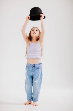 Şirin küçük kız siyah bir şapkayla oynuyor. Çocuk annesinin kıyafetlerini dener..